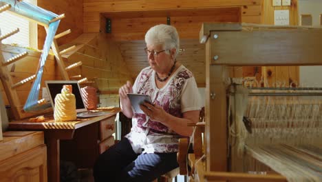 front view of old caucasian senior woman working on digital tablet in a workshop 4k