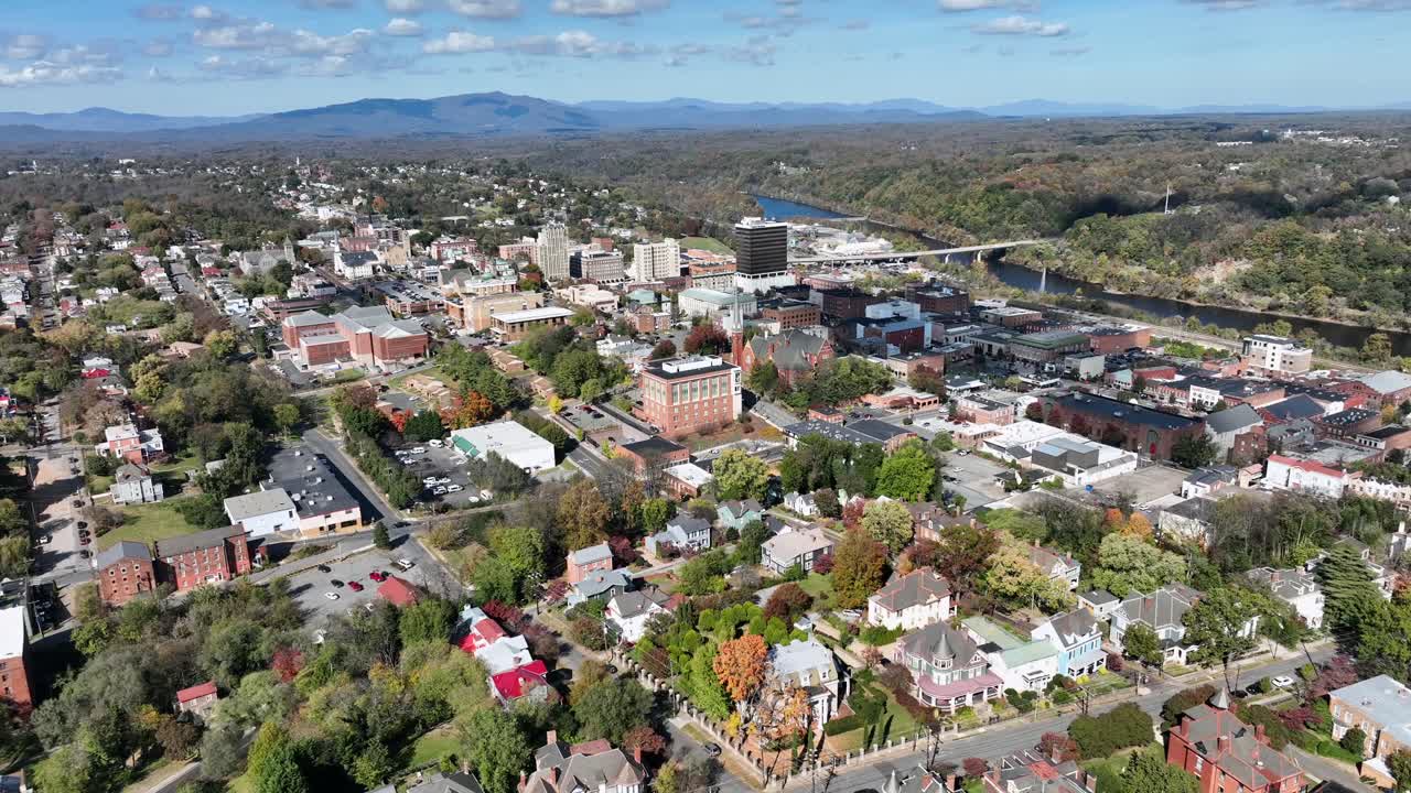 American downtown and neighborhood with houses and homes. Sunny day in autumn with Flowing River in background. Aerial wide shot. Top view.