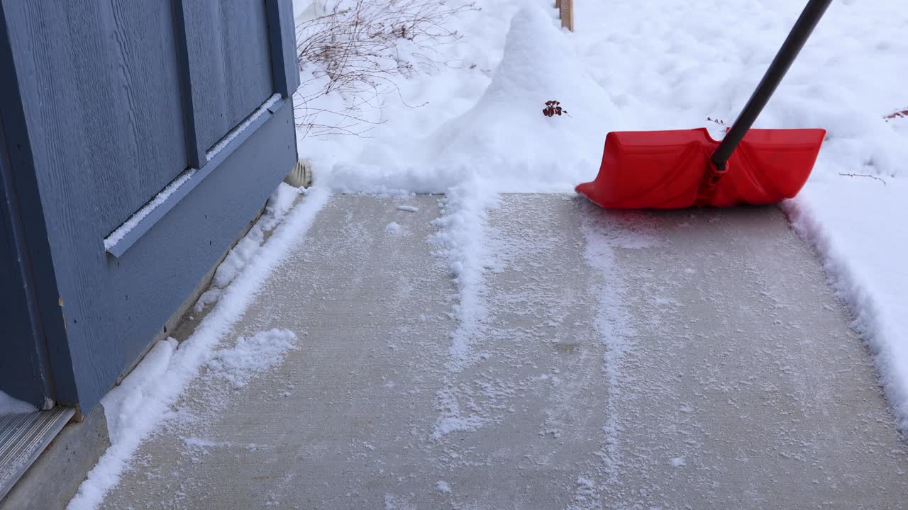 Skovler sne af verandaen om vinteren