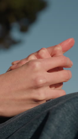 fotografía en primer plano de las manos de una persona frotándose, lo que sugiere una profunda contemplación o pensamiento. la cara de la persona no es visible, sólo se pueden ver pantalones vaqueros azules y un abrigo marrón, un momento reflexivo