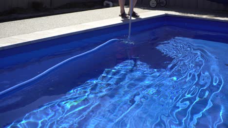 Hombre-Aspiradora-Piscina-Azul-En-El-Patio-Trasero