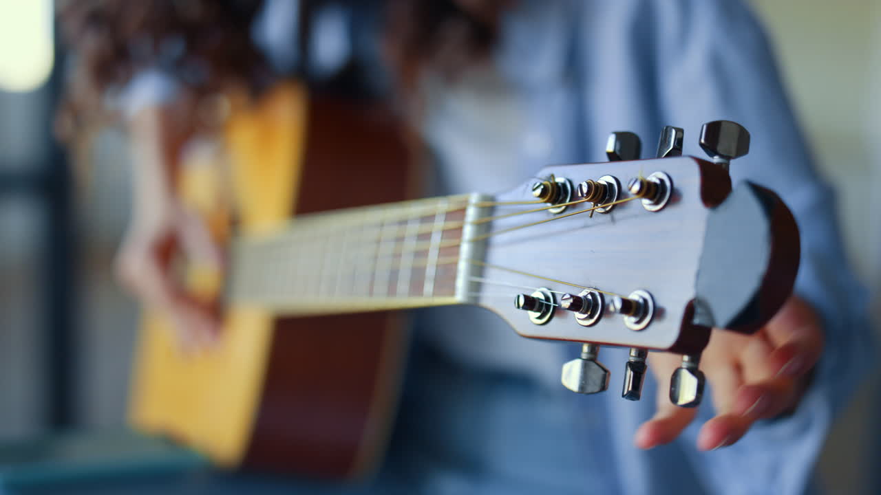 Girl hands tuning guitar. Young woman checking pegs of acoustic guitar
