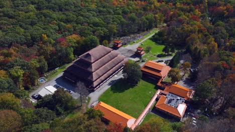 an aerial view of the chuang yen monastery on a sunny fall day, the leaves of the trees begin to change for the autumn season