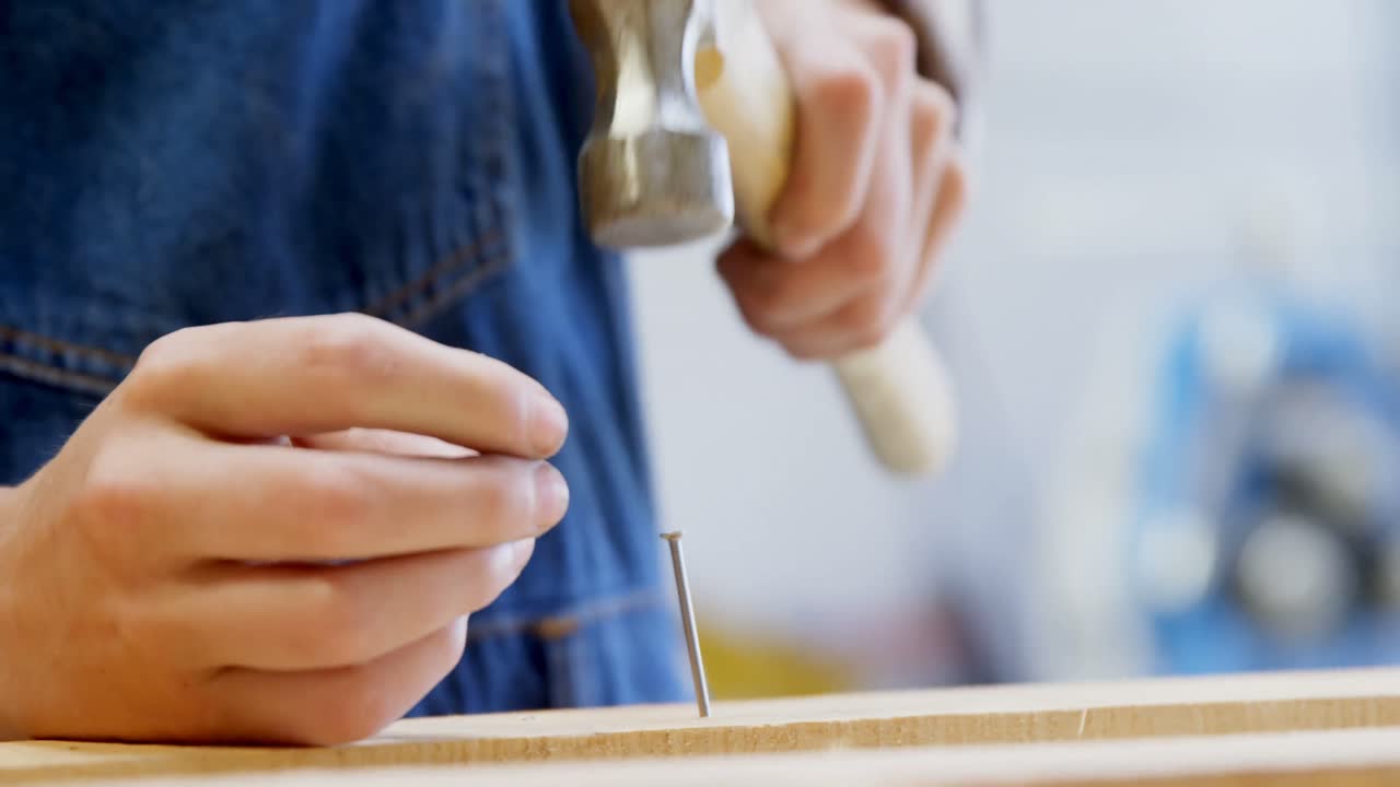 soldadora martillando un clavo en una tabla de madera 4k