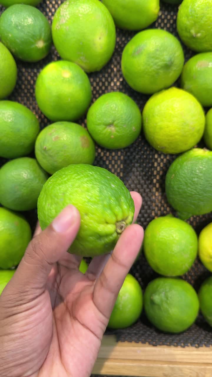 Mão Segurando e Girando uma Lima Verde Fresca