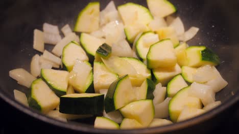 saltear calabacines picados y cebollas en una sartén humeante