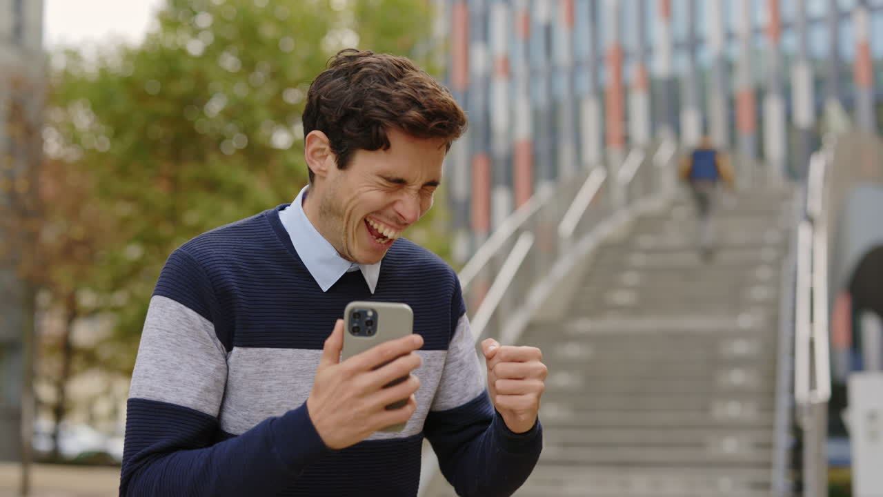 Excited Man Celebrating Success with Mobile Phone in Urban Setting