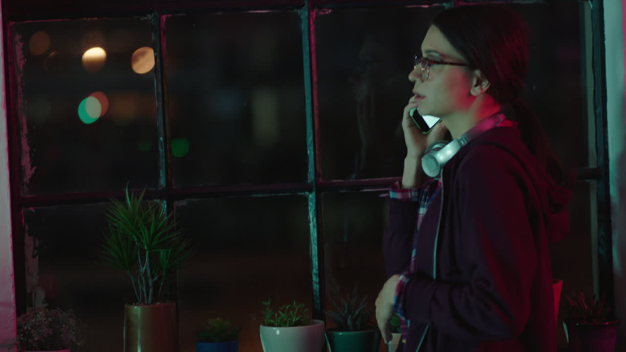 스마트폰을 사용하여 늦게 일하는 젊은 백인 사업가 여자 사업가 밤에 사무실에서 휴대전화로 이야기하는 기한에 대해 논의하는 전화 통화 대화