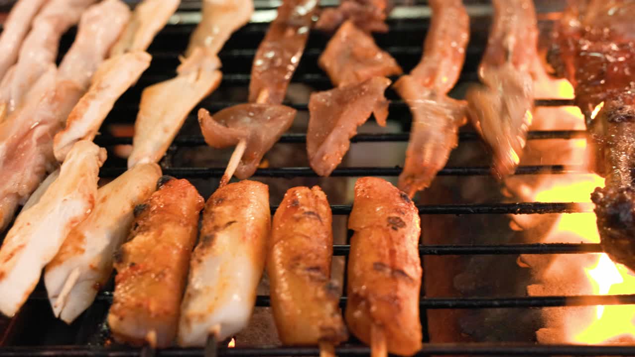 뜨거운 불꽃으로 숯불 그릴에 모듬 바비큐 고기를 굽는 노점상 패닝 샷