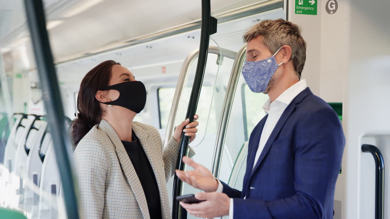 비즈니스 통근객 들 은 전염병 기간 에 ppe 얼굴 마스크 를 착용 한 휴대 전화 를 들고 열차 차량 에 서 있다