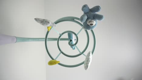 A newborn looks at a children's mobile with toys lying in a cradle. First-person view from the bottom up.