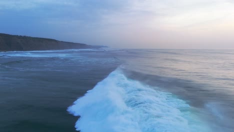 fuertes olas del océano atlántico chocando en la playa de magoito, portugal durante la hora azul