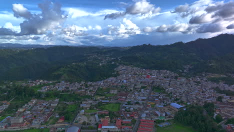 drone timelapse of chichicastenango, guatemala, showing the city stretching toward forested hills with bright sunlight and moving clouds
