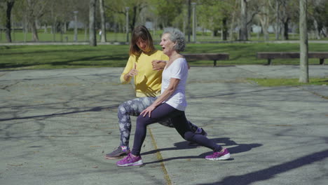 Side-view-of-one-woman-showing-lunge-exercise,-another-repeating