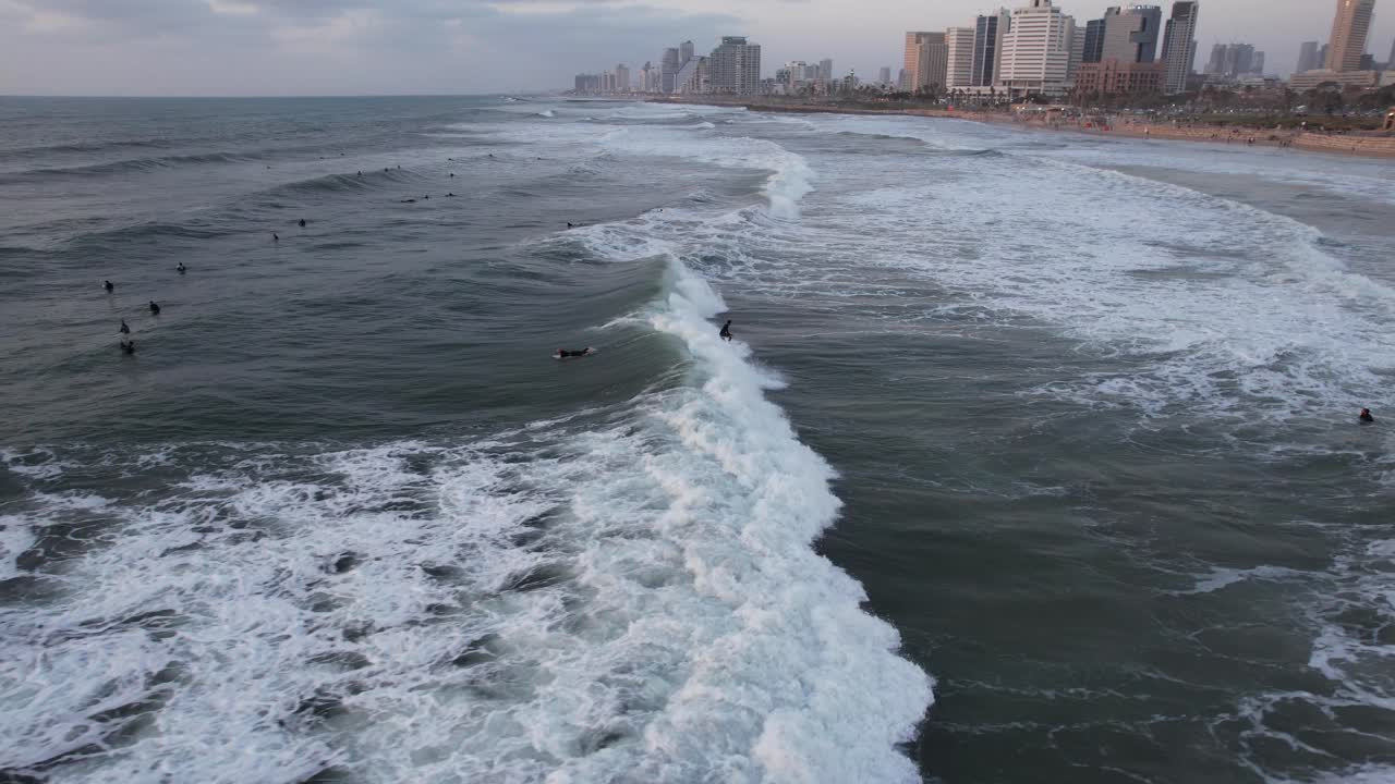 vista aérea de muchos surfistas, montando olas con el fondo del horizonte de tel aviv - seguimiento, disparo de drones