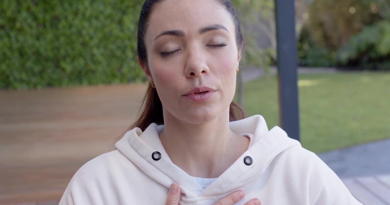Placing hands on chest and abdomen, female wearing hooded sweatshirt centering breath on deck