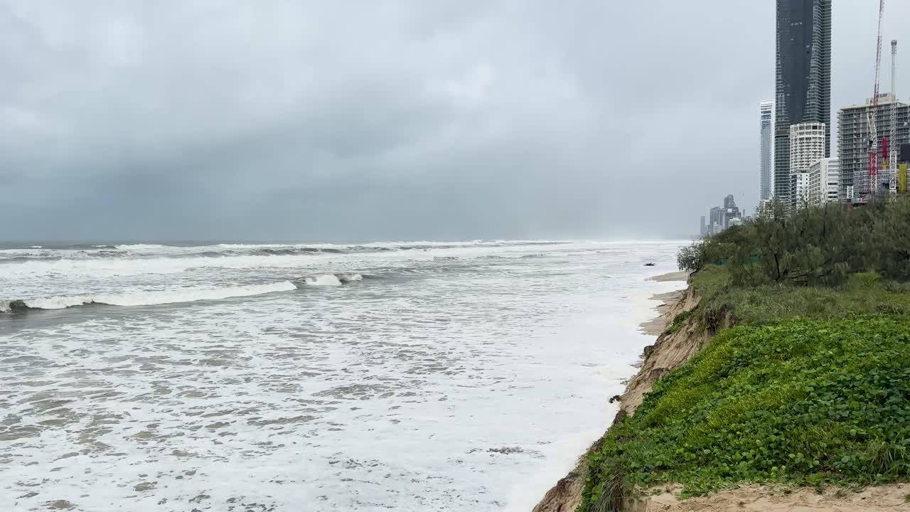 폭풍의 해변 장면은 침식과 격동의 파도를 보여줍니다. 구름이 가득한 하늘 아래, 해안선에 사이클론의 영향을 강조합니다.