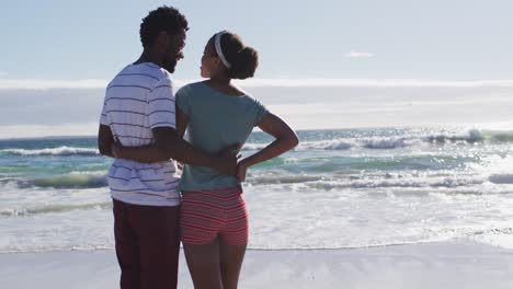 african american couple smiling and embracing on the beach