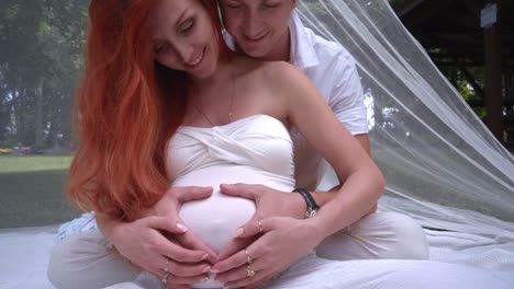 happy couple hugging pregnant belly. couple hands in heart on pregnant belly