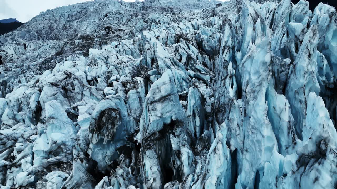 Close aerial view of Vatnajökull’s jagged glacier wall, revealing towering blue ice, deep crevasses, and rugged frozen terrain shaped by years of Arctic pressure