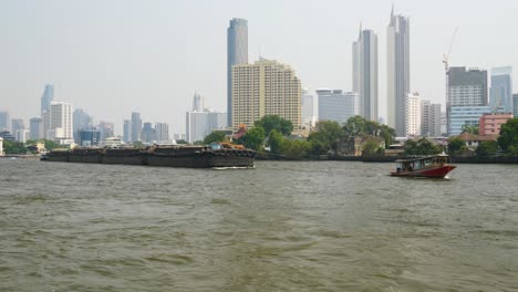 a small boat navigates the bustling chao phraya river in bangkok, thailand, transporting cargo