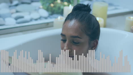woman soaking in bathtub amid pillar candles and pebbles, displaying equalizer bars for wellness