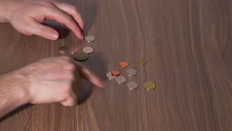 Man&#039;s Hands Counting Money on a Table with Thai Coins