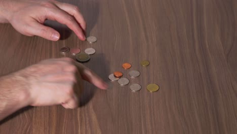 man's hands counting money on a table with thai coins