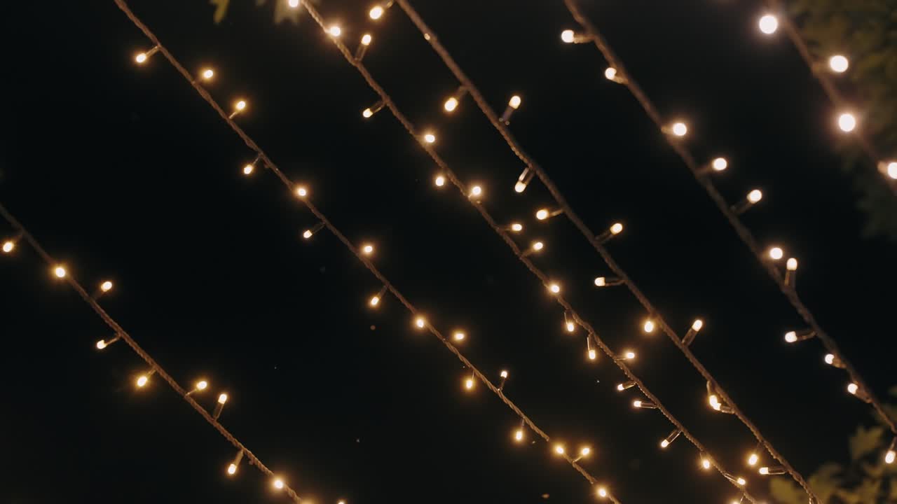 rows of glowing string lights illuminate the dark evening sky