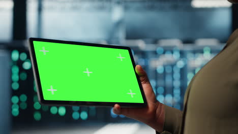 close up of technician at work using green screen tablet in data center