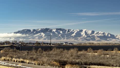 clouds moving in different directions and shadows cross the distant snowy mountain - static time lapse