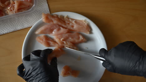 woman cutting chicken meat into slices on a plate