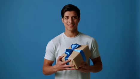 young man offering a gift box with blue ribbon