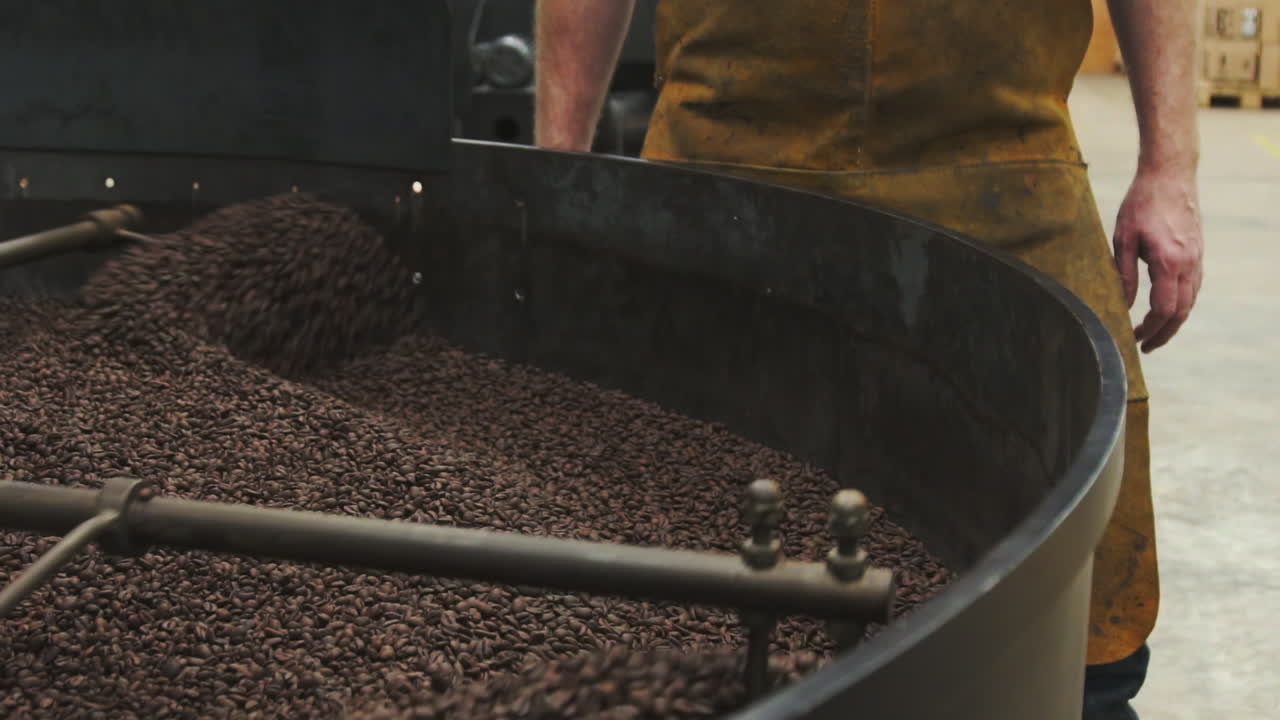 мужчина стоит у машины, перемешивающей бобы