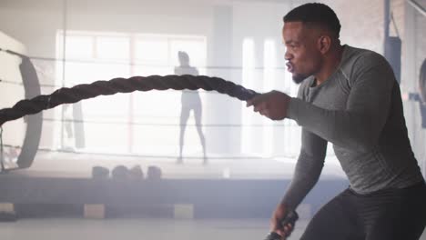 video de un hombre afroamericano en forma entrenando con cuerda en el gimnasio