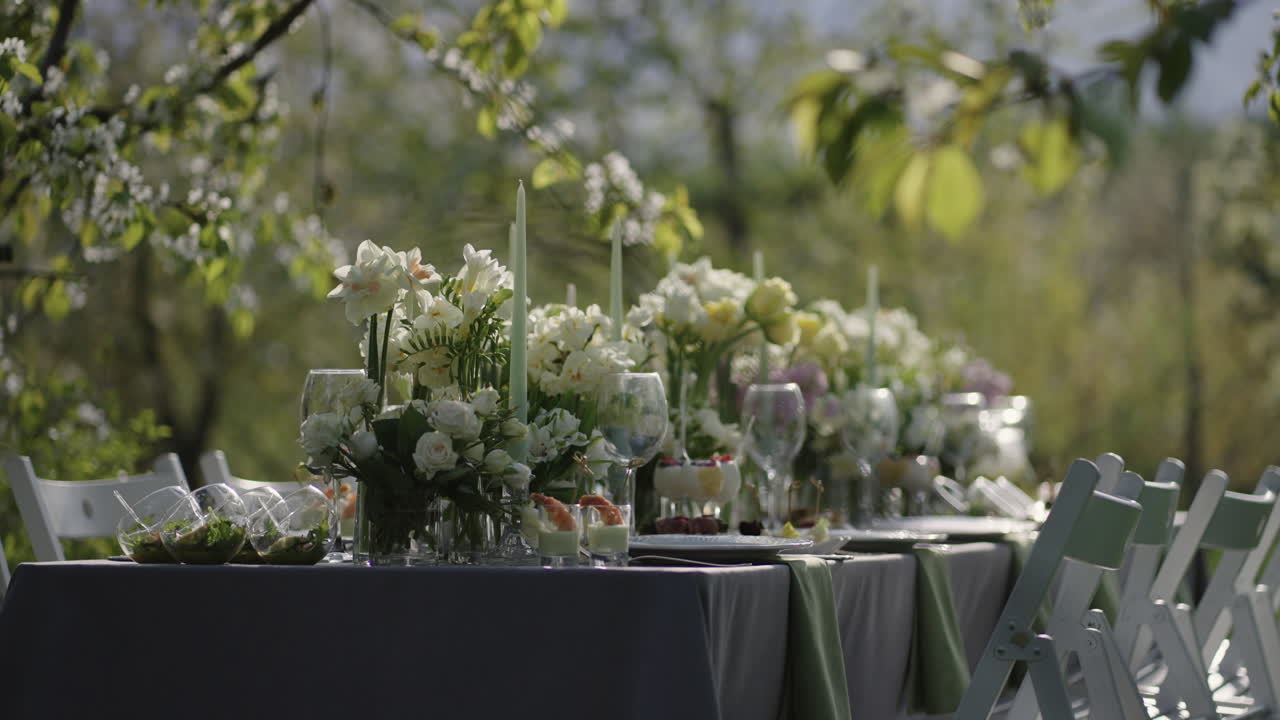 tavolo da pranzo con decorazione floreale in giardino in fiore in primavera atmosfera romantica di matrimonio in natura