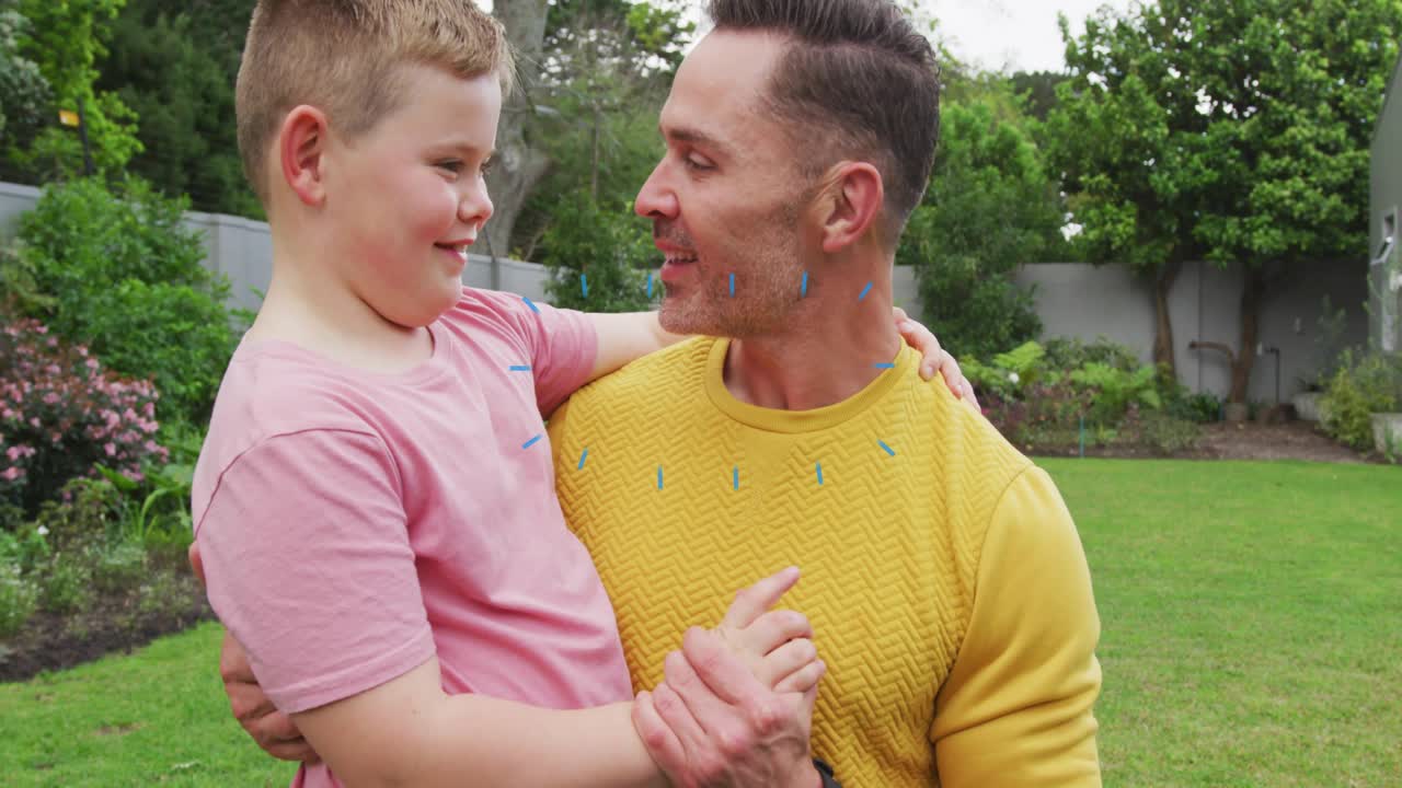 Padre che tiene in braccio il figlio in giardino, coriandoli che appaiono e provocano risate, avvicinandosi, marketing.