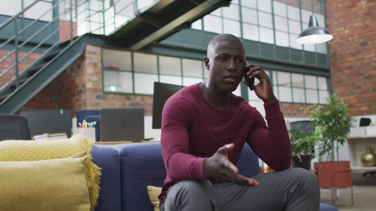 Felice uomo d'affari afroamericano che parla al telefono in ufficio.