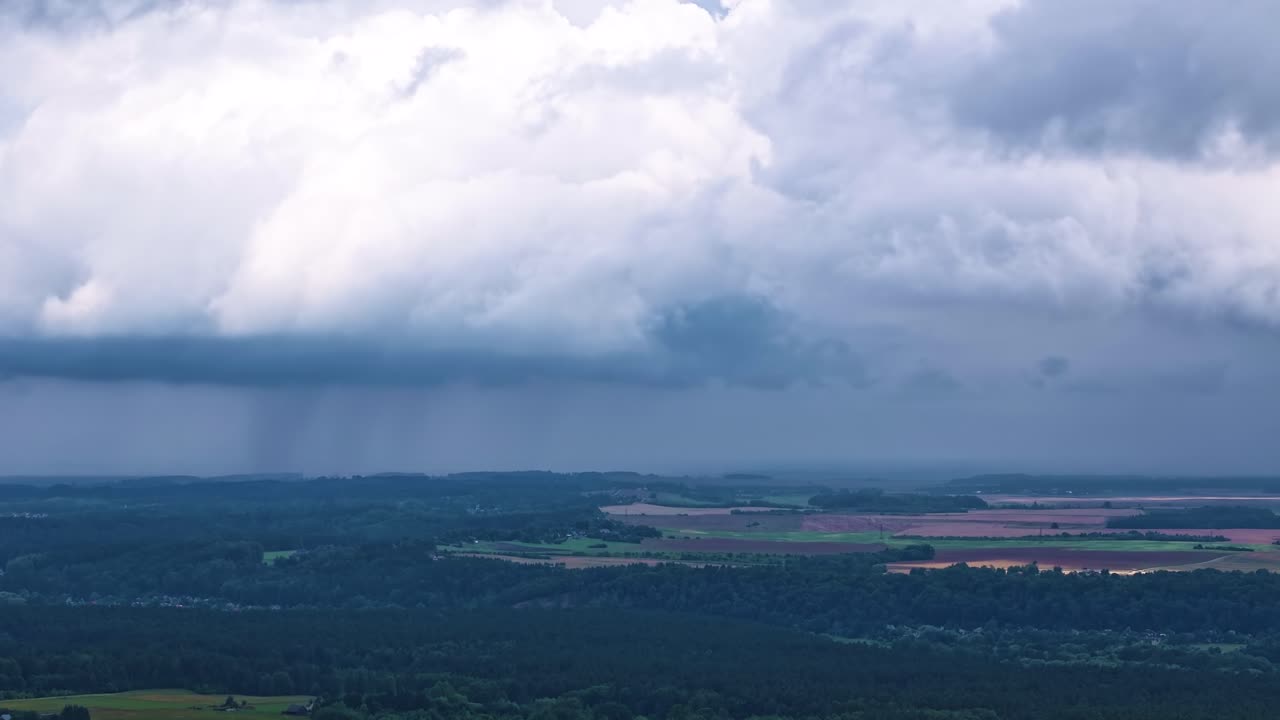 Deadly storm clouds above woodland landscape, aerial time lapse view