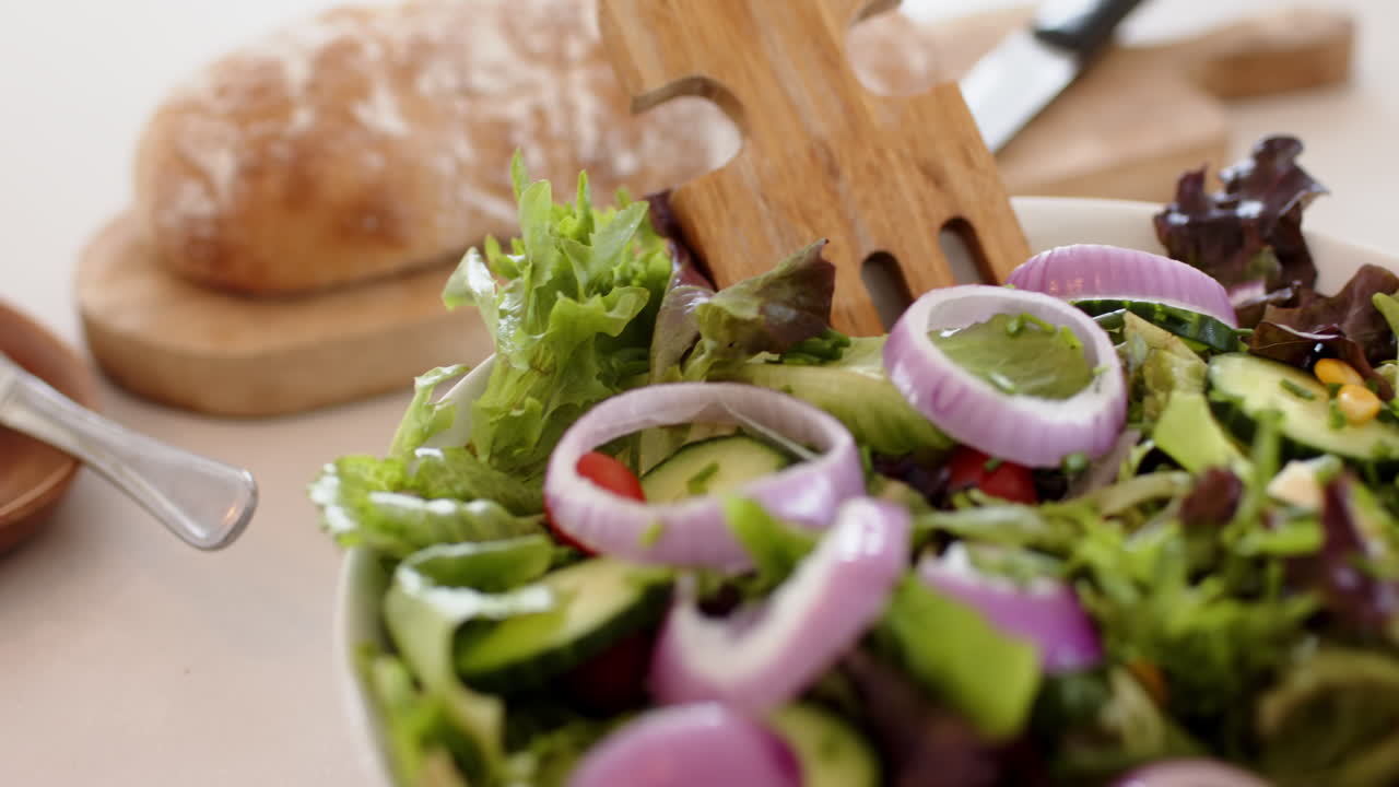 Preparing fresh salad with vegetables and bread in kitchen, healthy eating