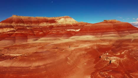 Utah-Bentonite-Hills-Drone-Shot-Reveal-of-Man-Running-on-Cliff