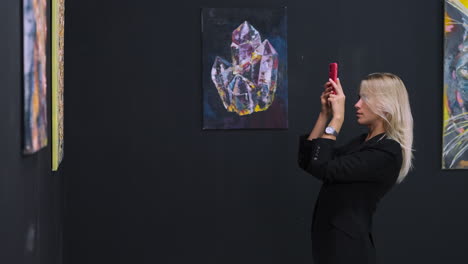 woman in art gallery taking pictures of paintings