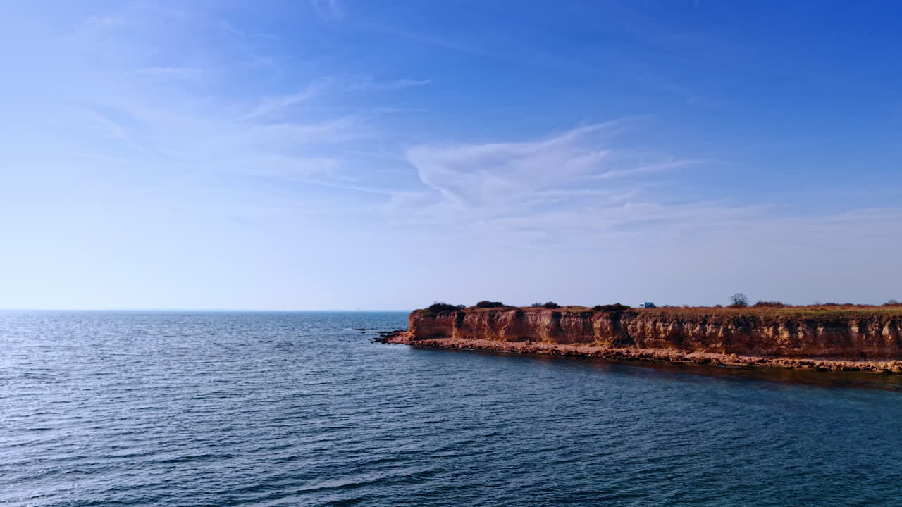 Avvicinamento alla riva di arenaria che si insinua nel paesaggio acquatico. Un camper si trova sulla costa del Mar Nero