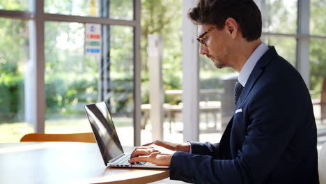 businessman at table working on laptop in modern office