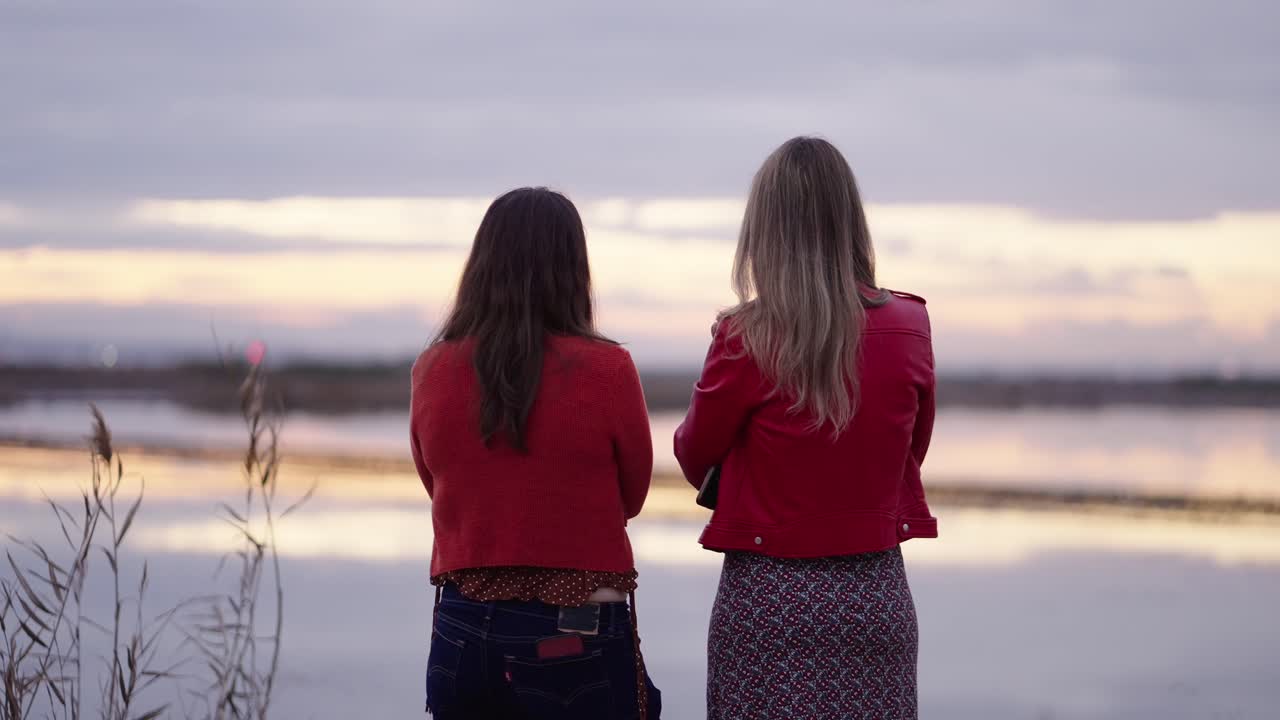Two Women Talking by the Lake at Sunset