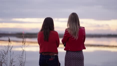 two women talking by the lake at sunset