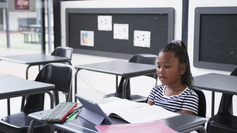 A-young-African-American-girl-raises-her-hand-in-classroom,-copy-space