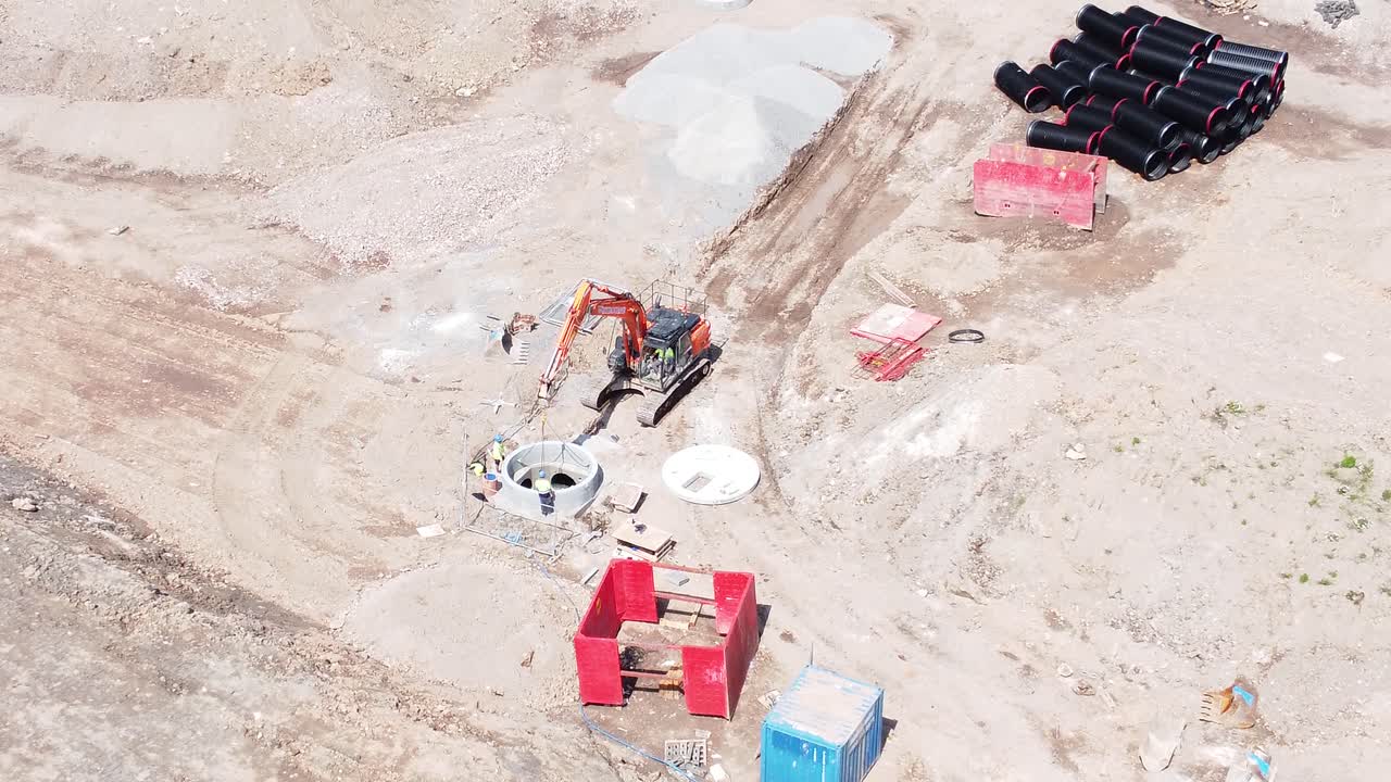 vehículo excavadora de excavación que prepara el conducto de tubería de hormigón vista aérea en el sitio de construcción del desarrollo de viviendas empuje hacia la izquierda