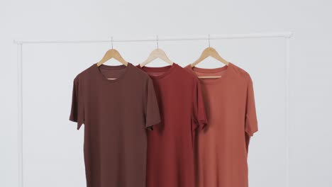 Video-of-three-brown-t-shirts-on-hangers-and-copy-space-on-white-background