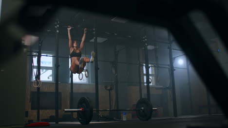 slow motion: raising feet up to bar on gym bar attractive muscle woman exercise and train in gym. female athlete standing on a horizontal bar lifts her legs to train the muscles of the abs